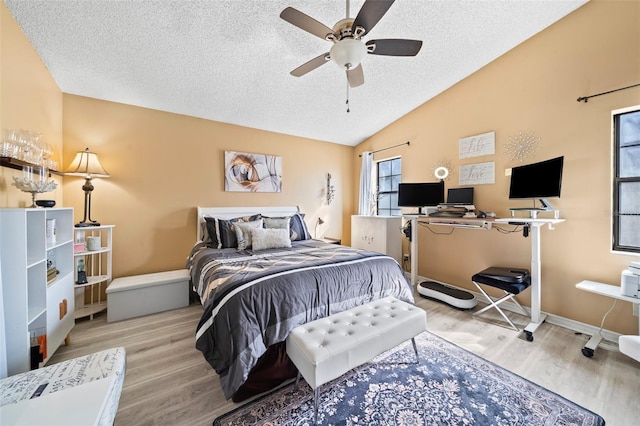 bedroom with vaulted ceiling, light hardwood / wood-style flooring, a textured ceiling, and ceiling fan