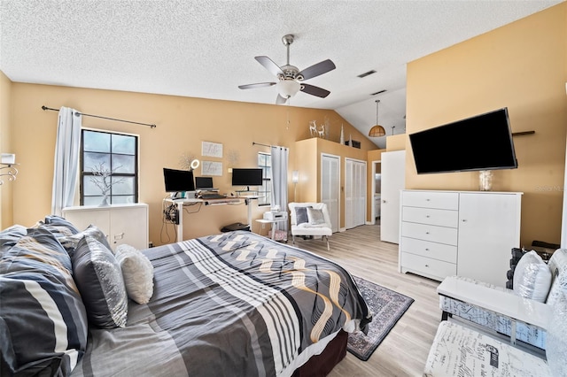 bedroom featuring ceiling fan, a textured ceiling, vaulted ceiling, and light hardwood / wood-style flooring