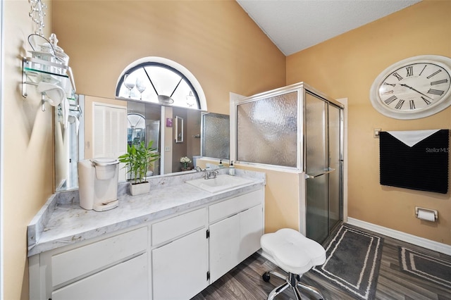 bathroom with vanity, wood-type flooring, high vaulted ceiling, and walk in shower