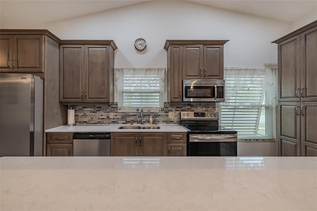 kitchen featuring backsplash, appliances with stainless steel finishes, sink, and vaulted ceiling