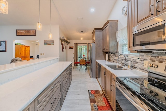 kitchen with a healthy amount of sunlight, stainless steel appliances, sink, and decorative light fixtures