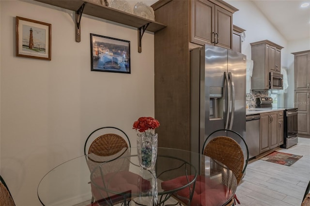 dining room featuring lofted ceiling, sink, and light hardwood / wood-style floors