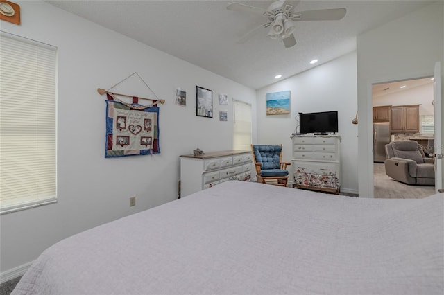 carpeted bedroom with vaulted ceiling, stainless steel refrigerator, and ceiling fan