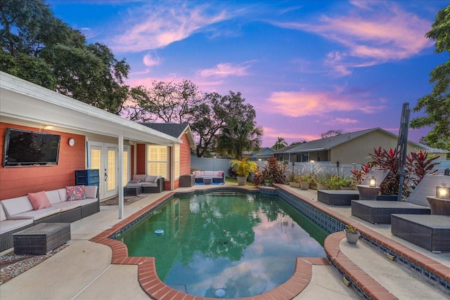 pool at dusk with french doors, an outdoor living space, and a patio area