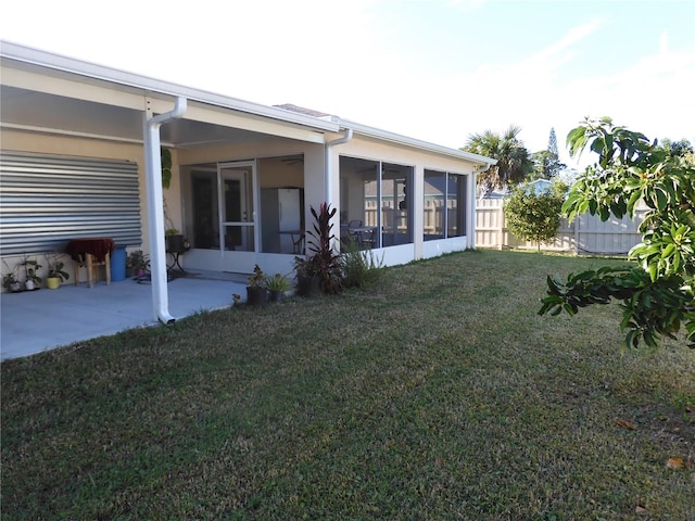 rear view of house with a yard, a patio, and a sunroom