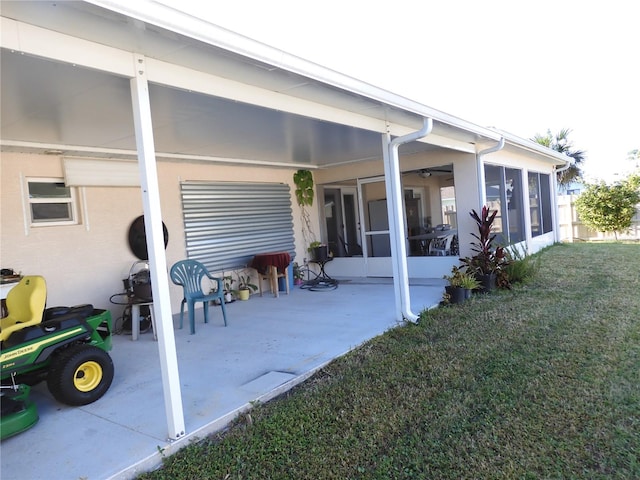 back of house featuring a yard, a patio, and a sunroom