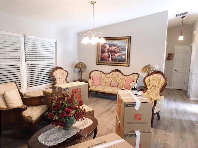 living room featuring light hardwood / wood-style floors, lofted ceiling, and a chandelier