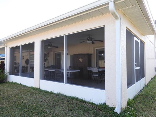 exterior space with a yard, ceiling fan, and a sunroom