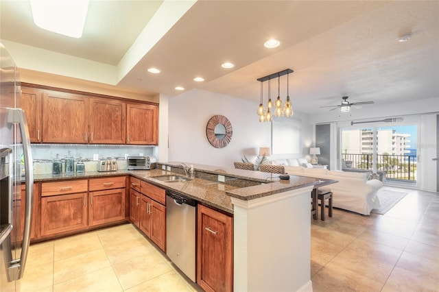 kitchen featuring kitchen peninsula, dark stone countertops, sink, pendant lighting, and stainless steel appliances