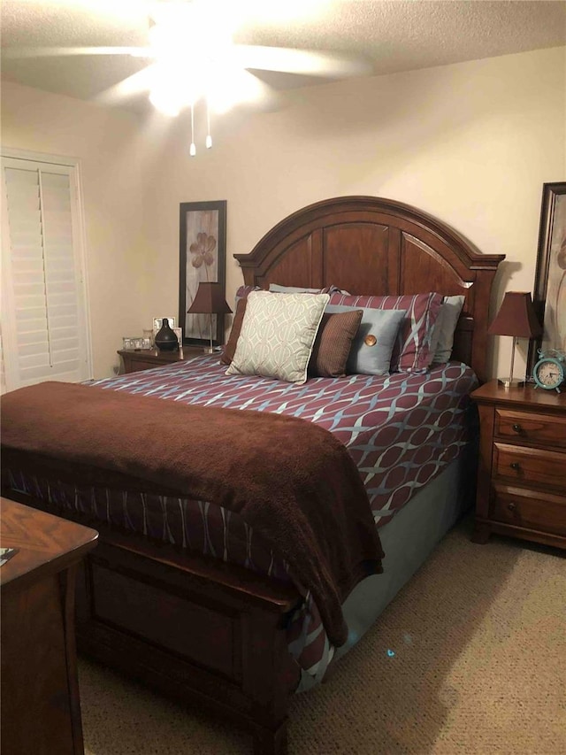 bedroom with ceiling fan, carpet floors, and a textured ceiling