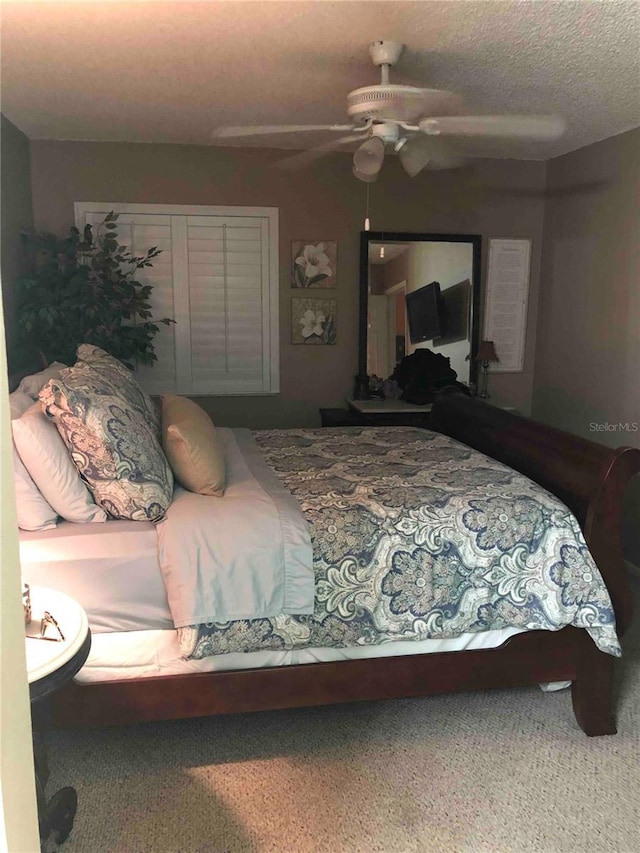 carpeted bedroom with ceiling fan and a textured ceiling