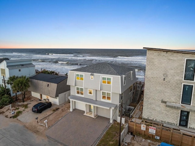 aerial view at dusk with a water view and a beach view