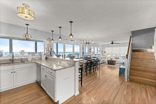 kitchen with white cabinets, sink, light wood-type flooring, and pendant lighting