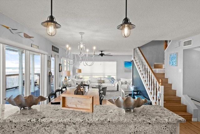 kitchen featuring hardwood / wood-style floors, decorative light fixtures, ceiling fan with notable chandelier, and a textured ceiling