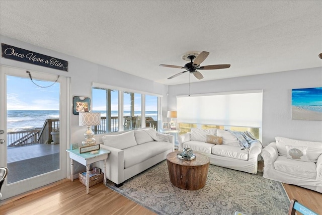 living room with hardwood / wood-style floors, a water view, and a textured ceiling