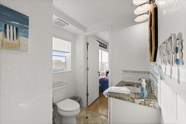 bathroom featuring vanity, toilet, a textured ceiling, and hardwood / wood-style floors