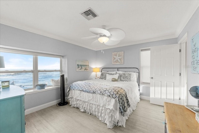 bedroom with a water view, ceiling fan, crown molding, and light wood-type flooring