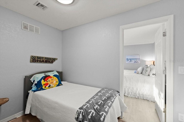 bedroom with hardwood / wood-style flooring and a textured ceiling