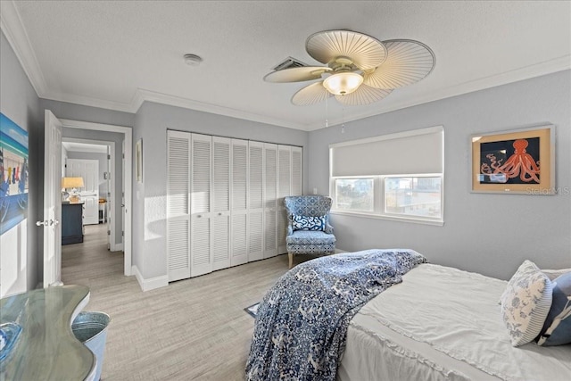 bedroom featuring a closet, crown molding, light wood-type flooring, a textured ceiling, and ceiling fan