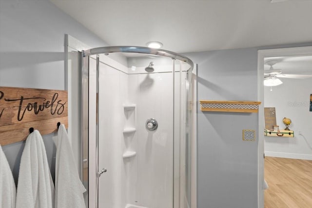 bathroom with a shower with shower door, wood-type flooring, and ceiling fan