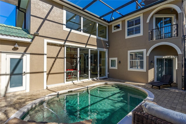 view of swimming pool featuring glass enclosure and a patio area