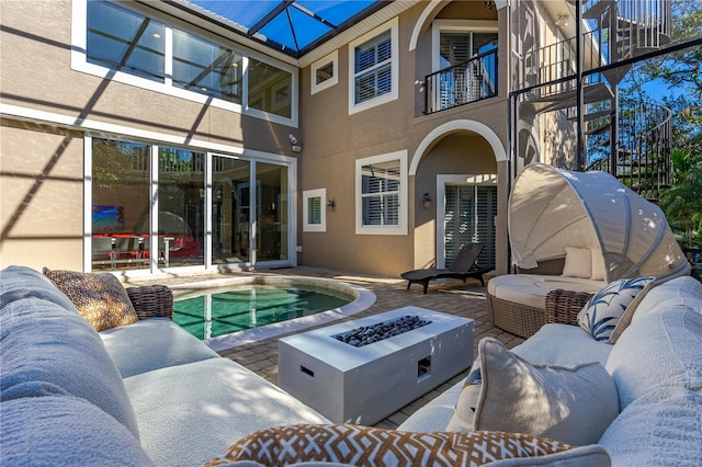 back of property with a patio area, a balcony, and an outdoor living space with a fire pit