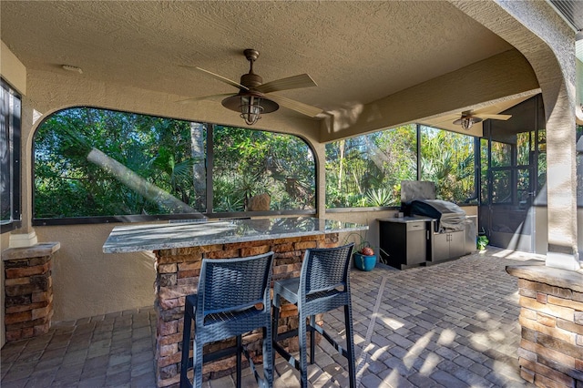 view of patio / terrace featuring a grill, ceiling fan, exterior bar, and exterior kitchen