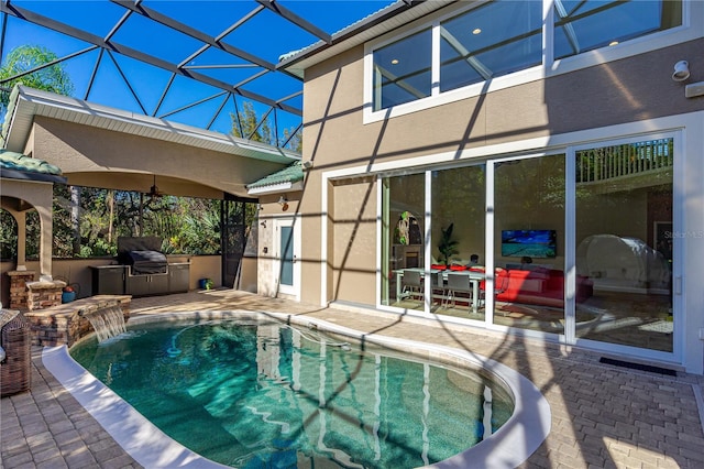 view of swimming pool with pool water feature, an outdoor kitchen, a patio, and grilling area