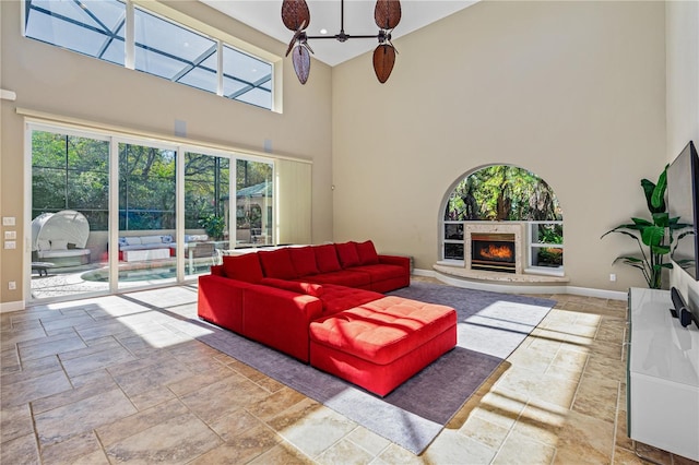 living room featuring ceiling fan, a healthy amount of sunlight, and a towering ceiling