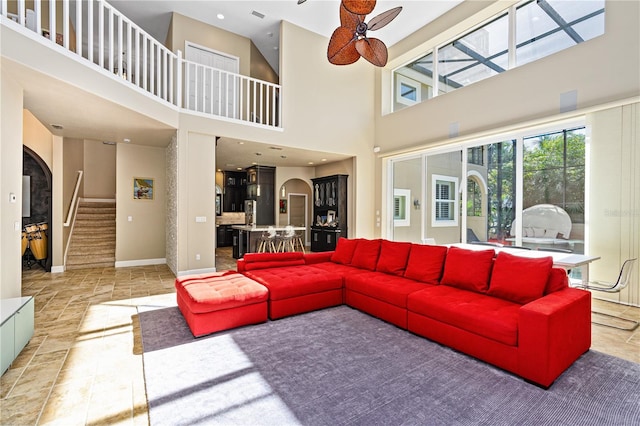 living room featuring ceiling fan and a high ceiling