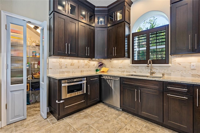 kitchen with light stone counters, sink, stainless steel appliances, and dark brown cabinets