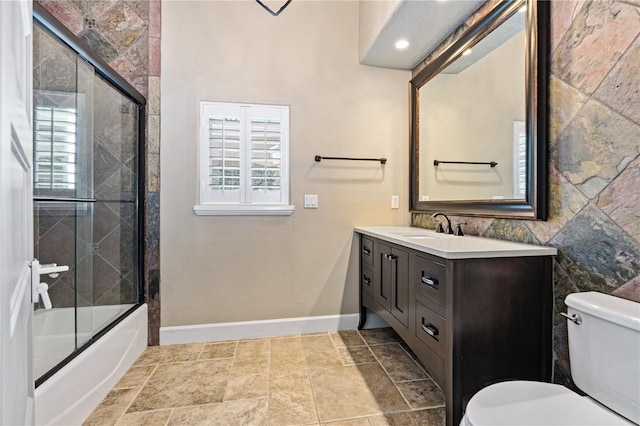 full bathroom with vanity, bath / shower combo with glass door, and toilet