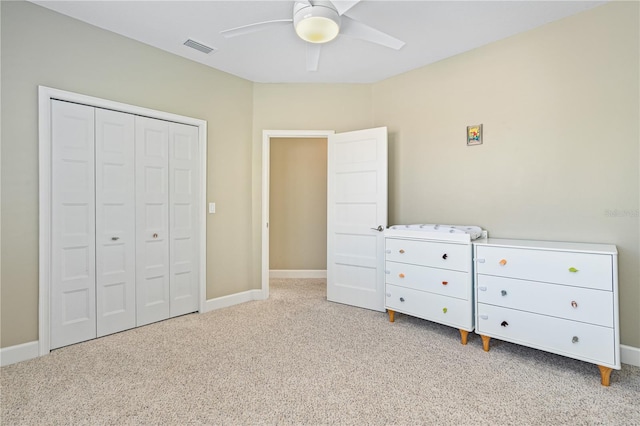 unfurnished bedroom featuring ceiling fan, light colored carpet, and a closet