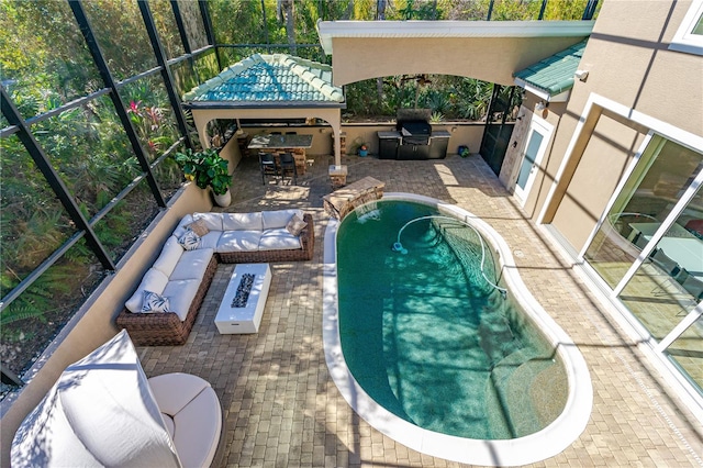 view of pool with an outdoor kitchen, glass enclosure, a fire pit, and a patio area