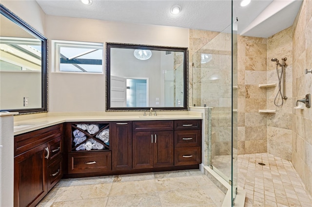 bathroom with a tile shower, vanity, and a textured ceiling