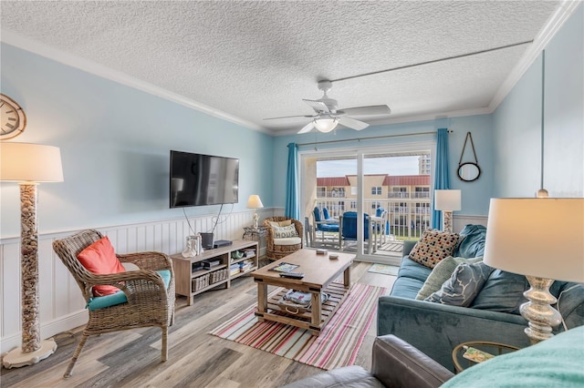 living room featuring ceiling fan, a textured ceiling, light hardwood / wood-style flooring, and crown molding