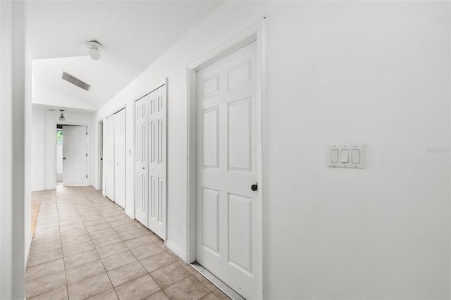 corridor featuring light tile patterned flooring and vaulted ceiling