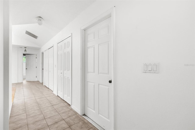 hallway featuring light tile patterned flooring and vaulted ceiling