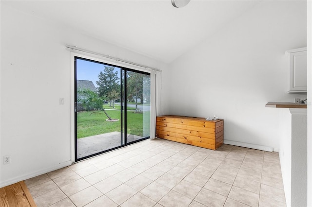 tiled spare room with vaulted ceiling