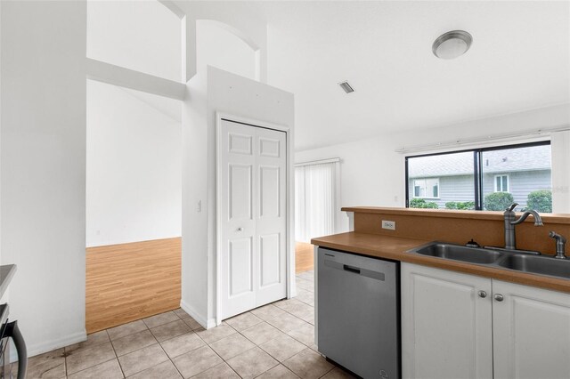 172 Gull Dr S, Daytona Beach, FL 32119 - kitchen with stainless steel dishwasher, a sink, white cabinetry, vaulted ceiling, and light tile patterned floors