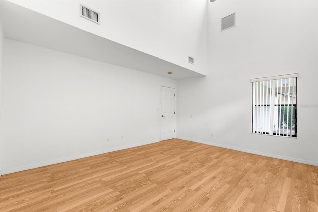 unfurnished room featuring a towering ceiling and light hardwood / wood-style flooring