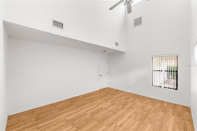 spare room featuring ceiling fan, a high ceiling, and light wood-type flooring