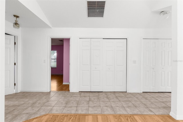 unfurnished bedroom with multiple closets and light wood-type flooring