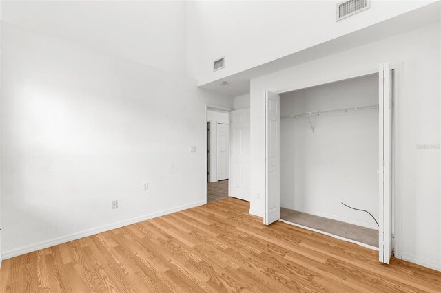 172 Gull Dr S, Daytona Beach, FL 32119 - unfurnished bedroom with light wood finished floors, baseboards, a closet, and a towering ceiling