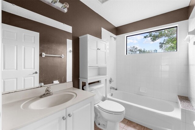 full bathroom with toilet, tile patterned flooring, tiled shower / bath, vanity, and a textured ceiling