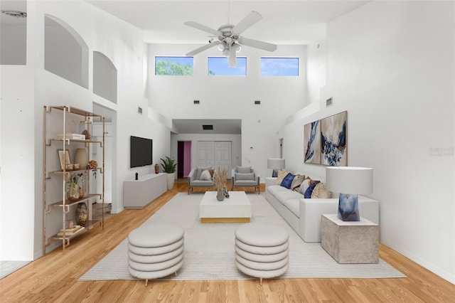 living room featuring ceiling fan, hardwood / wood-style flooring, and a high ceiling