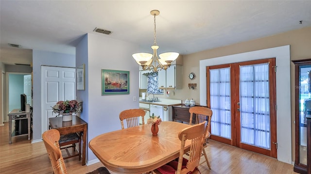 dining area with light hardwood / wood-style flooring, french doors, a chandelier, and sink