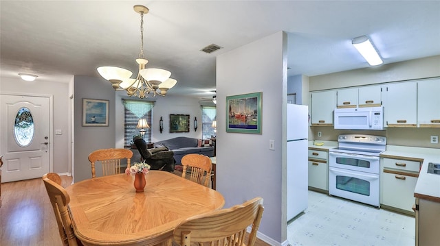 dining space with ceiling fan with notable chandelier and light hardwood / wood-style floors