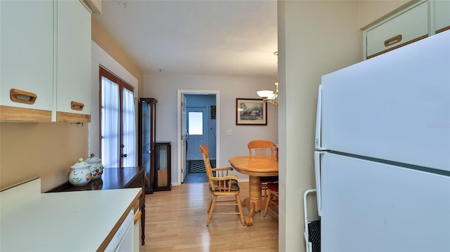 kitchen with pendant lighting, light hardwood / wood-style floors, white refrigerator, and white cabinets