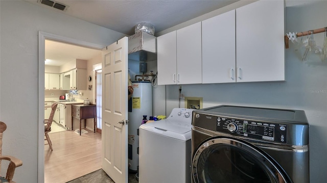 laundry area with hardwood / wood-style flooring, electric water heater, sink, cabinets, and washer and dryer